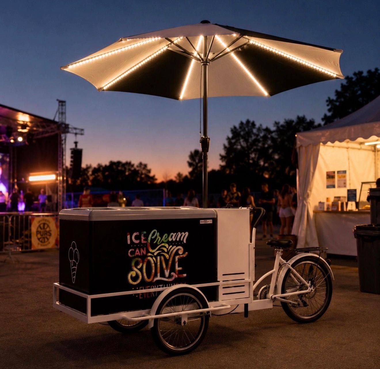 Eisfahrrad bei Nacht mit beleuchtetem Schirm auf Event