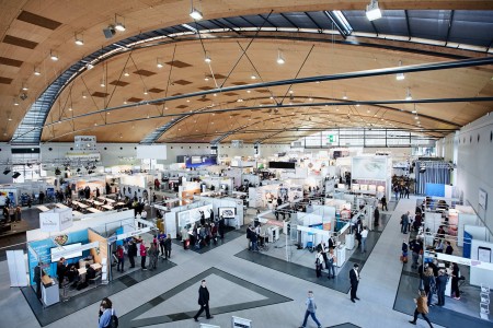 TIMELESS Messe- und Kongresspersonal im Einsatz in einer weitläufigen, modernen Messehalle mit zahlreichen Ausstellungsständen und Besuchern